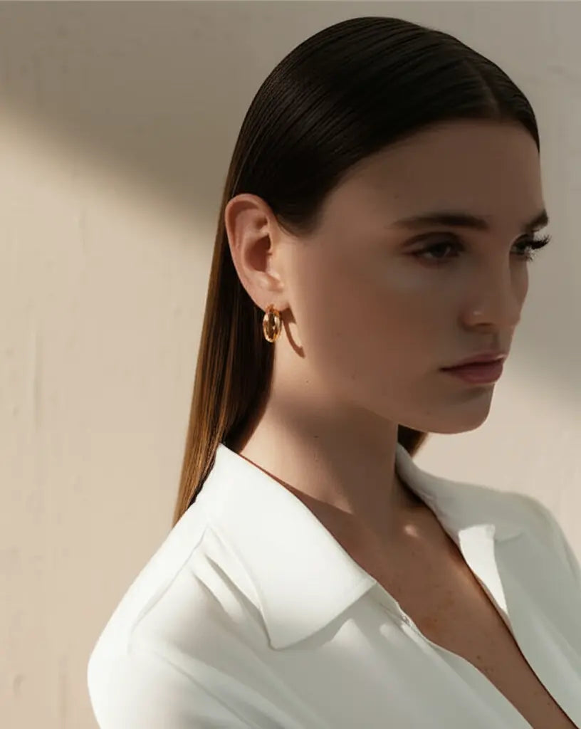 Woman wearing gold earrings with a neutral background