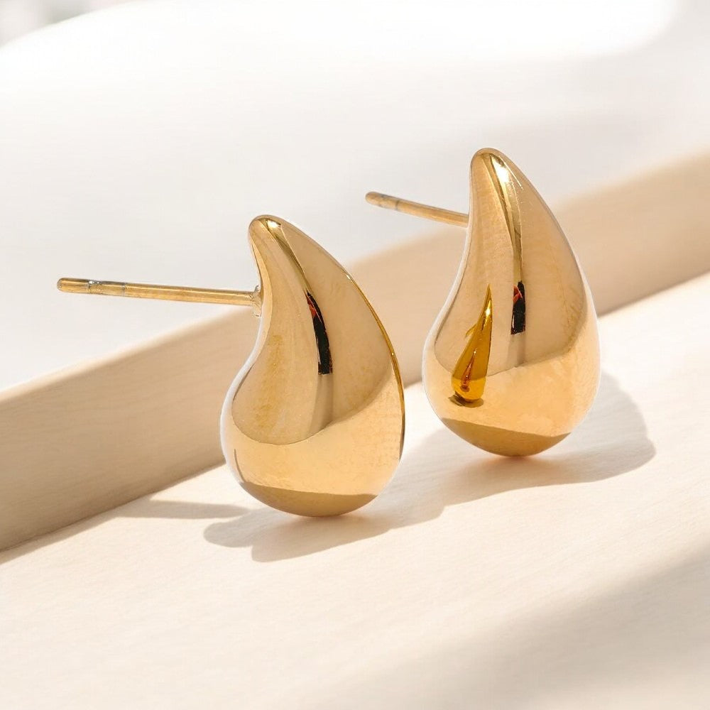 Gold teardrop earrings on a light background