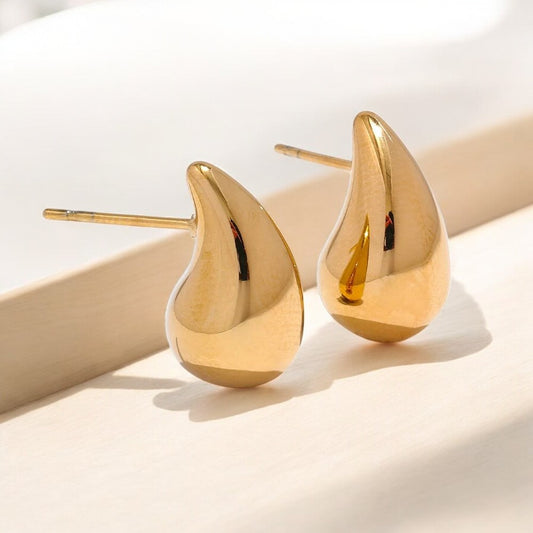 Gold teardrop earrings on a light background