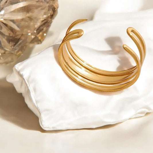 Gold bracelet on a white fabric surface with a soft focus background