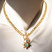 Gold necklace with a sun-shaped pendant featuring a turquoise stone on a white background