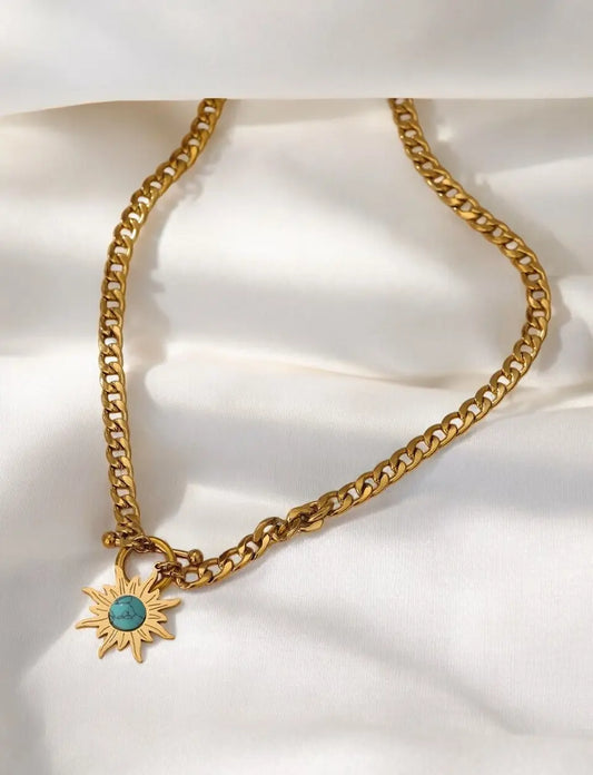 Gold chain necklace with a sun-shaped pendant on a white background
