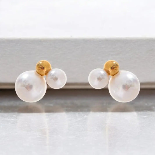 Pair of pearl earrings with gold tops on a white background