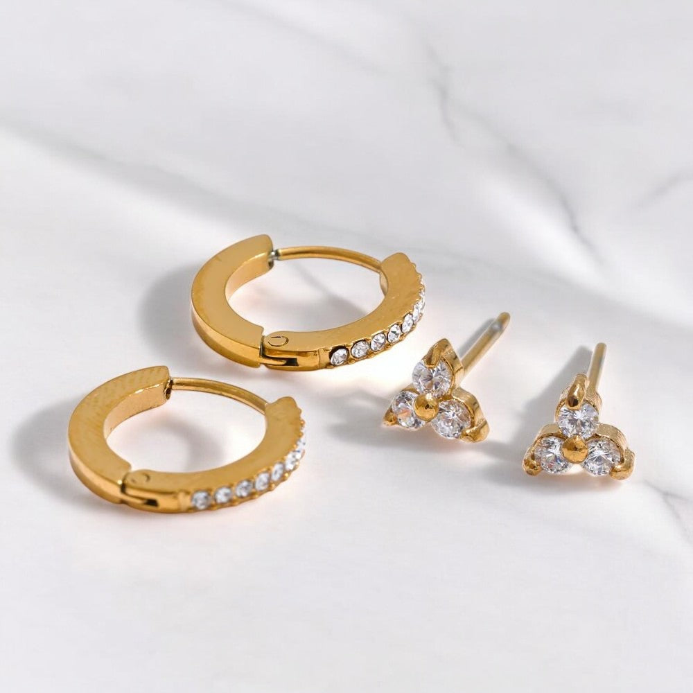 Gold hoop earrings and floral stud earrings on a white background