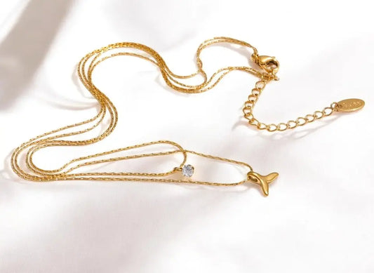 Gold necklace with a whale-shaped pendant on a white background