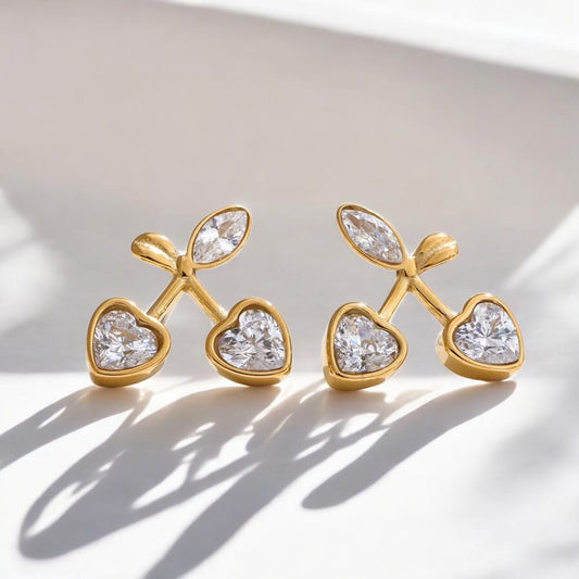 Pair of gold earrings with heart-shaped gemstones on a light background
