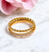 Gold ring with diamond accents on a marble surface with a pink flower.