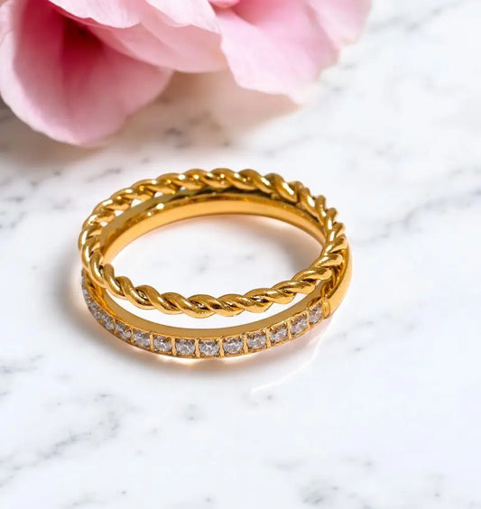 Gold ring with diamond accents on a marble surface with a pink flower.