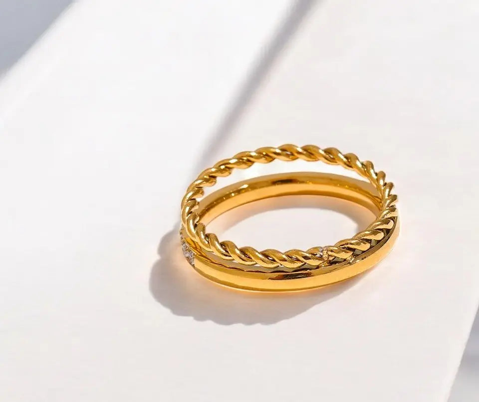 Gold ring with braided design on a white background