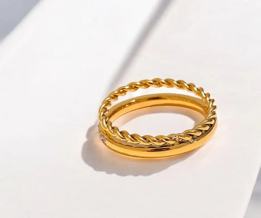 Gold ring with braided design on a white background