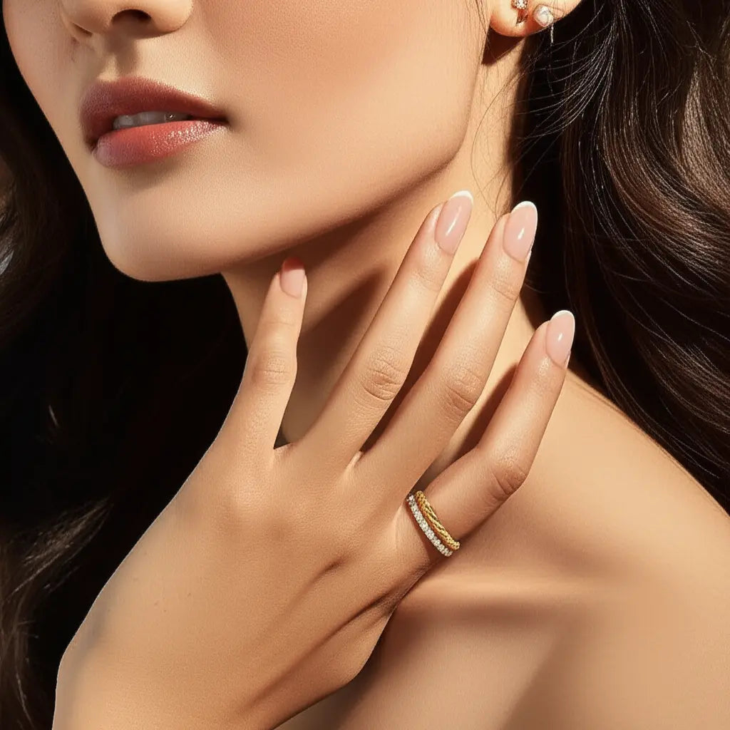 Close-up of a woman's hand with a gold ring and earring, touching her neck.