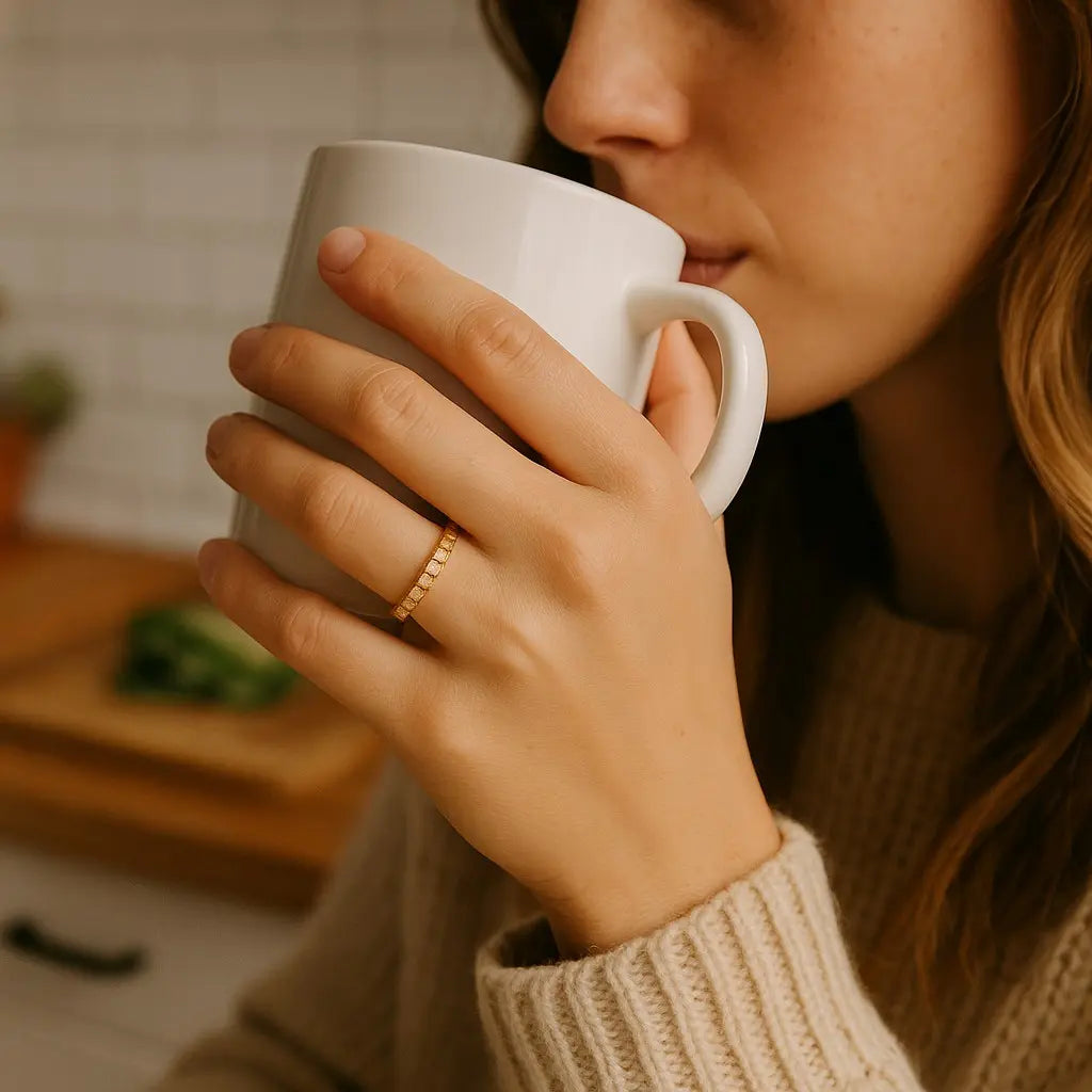 Person holding a white mug with a blurred kitchen background