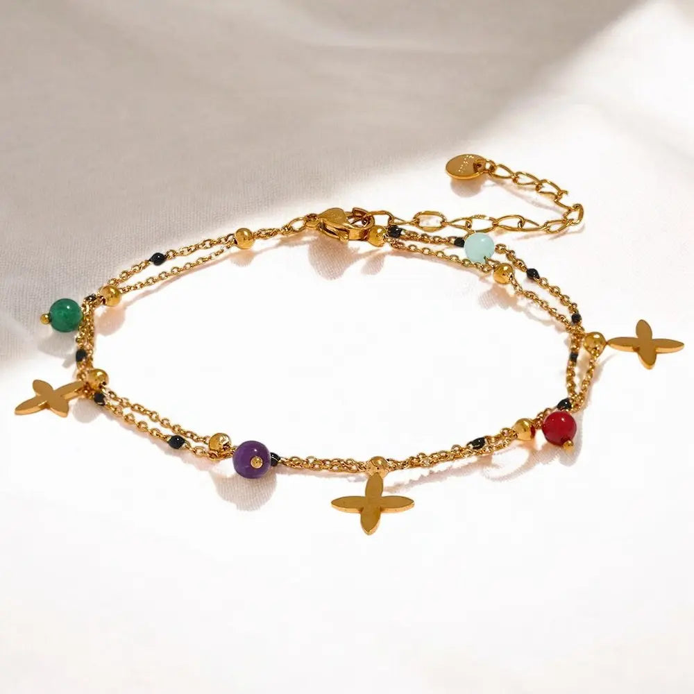 Gold anklets with colorful beads and charms on a white background