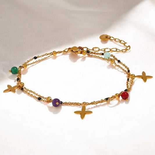 Gold anklets with colorful beads and charms on a white background
