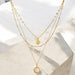 Two gold necklaces with pendants on a light background