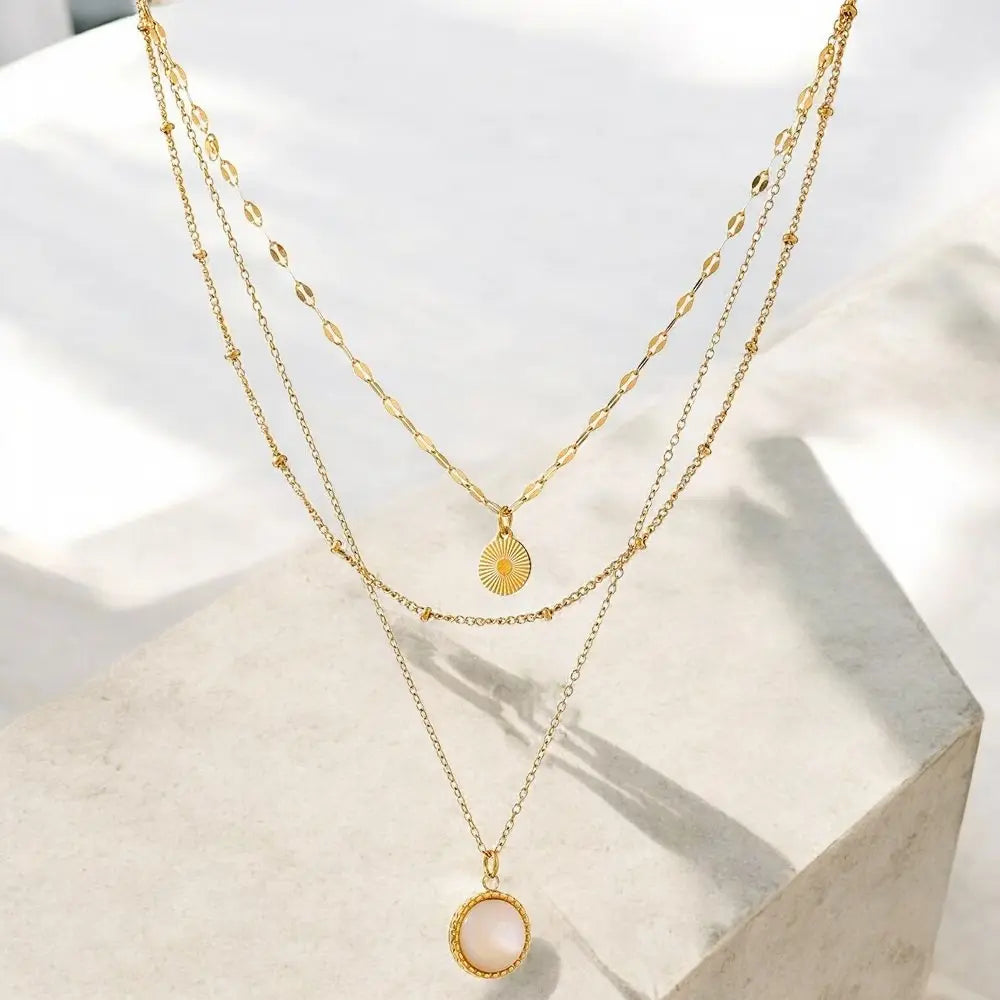 Two gold necklaces with pendants on a light background
