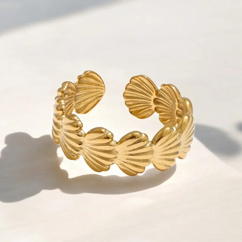Gold bracelet with shell-like designs on a light background