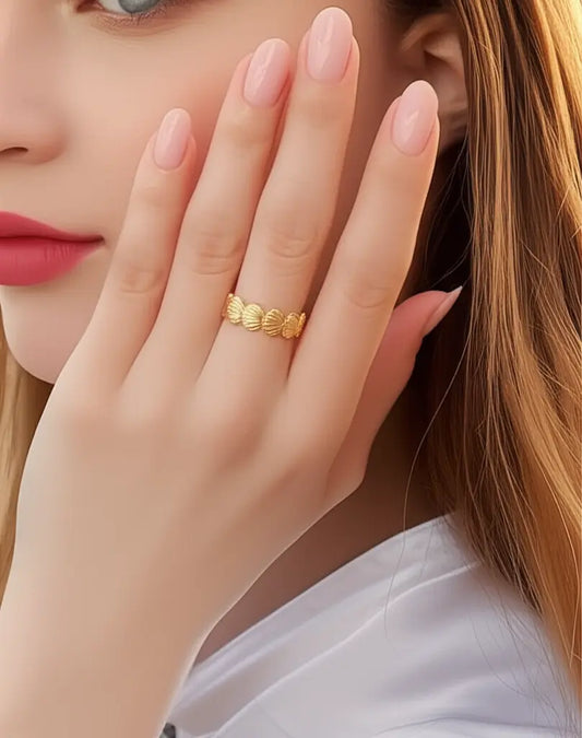 Close-up of a hand wearing a gold ring with a blurred background