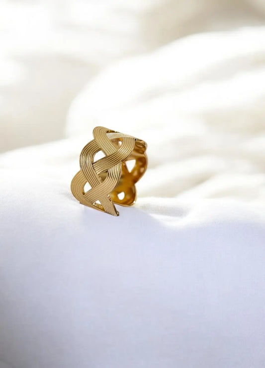 Gold ring with intricate design on a white surface