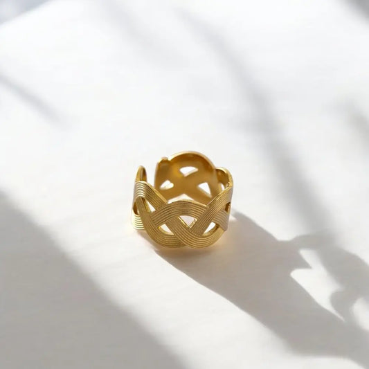 Gold bracelet on a white surface with soft shadows