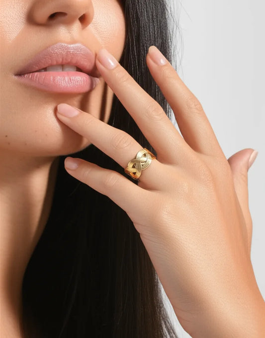 Close-up of a hand wearing a gold ring with a heart design, touching the face.