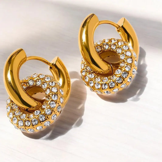 Gold hoop earrings with clear gemstones on a light background