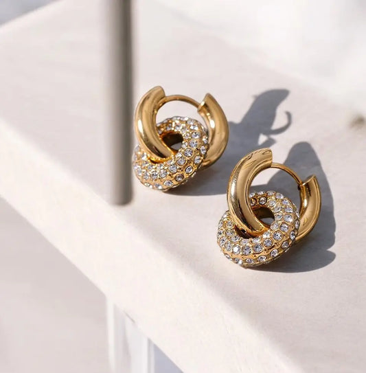 Gold hoop earrings with embedded crystals on a light background