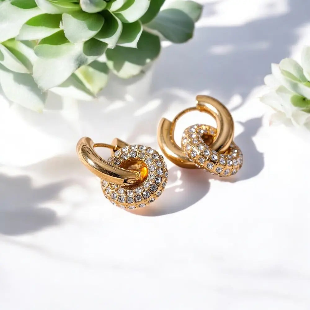 Gold hoop earrings with crystal details on a light background