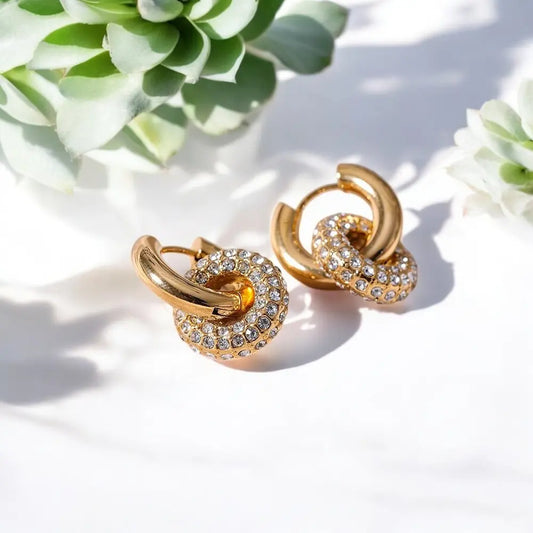 Gold hoop earrings with crystal details on a light background