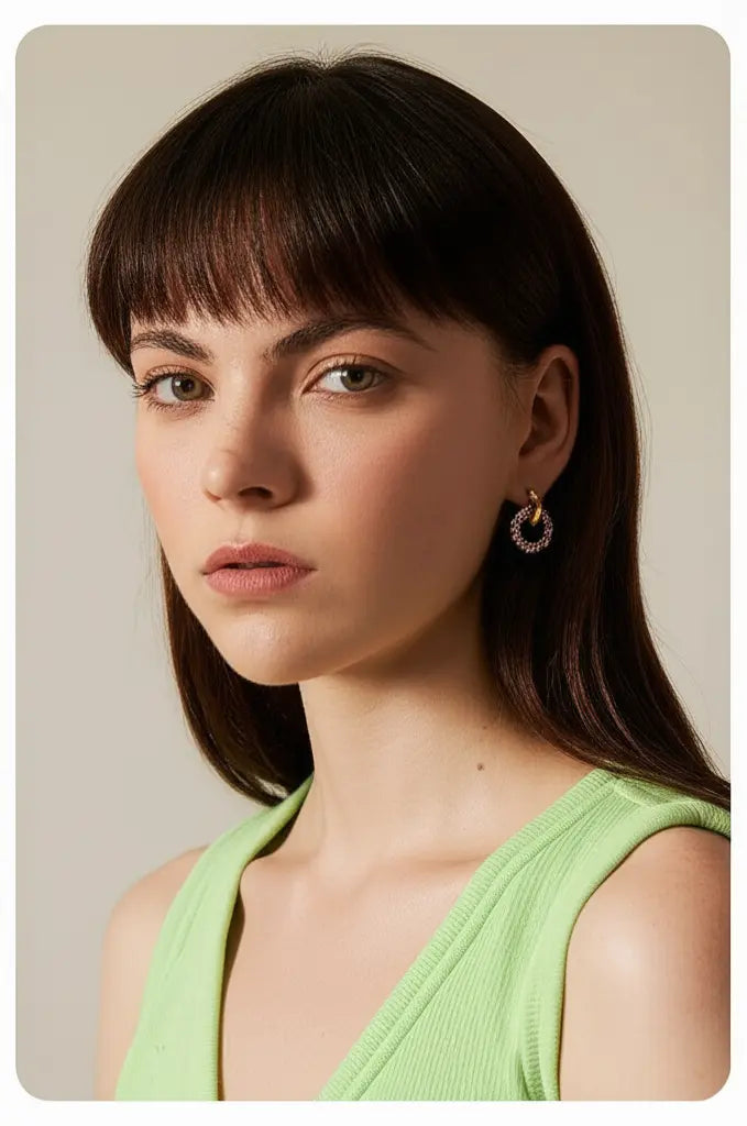 Woman with long dark hair wearing a green top against a neutral background