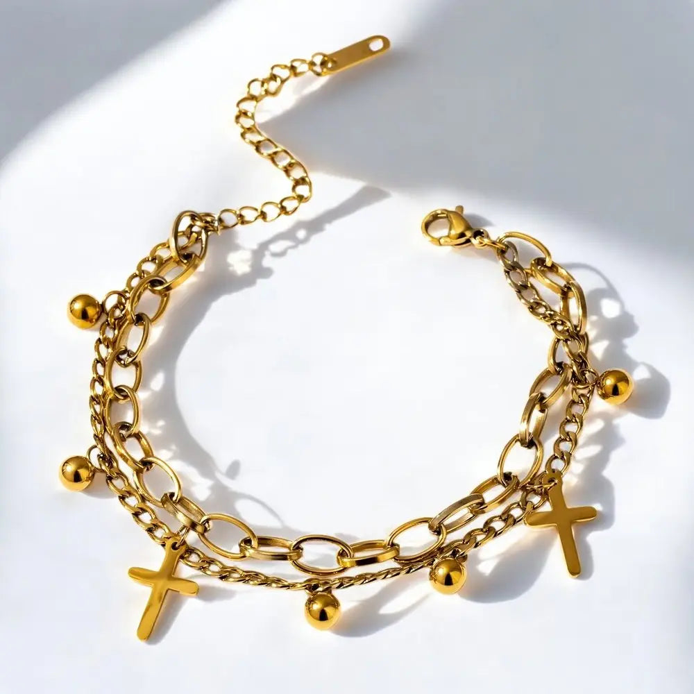 Gold chain bracelet with various charms on a white background
