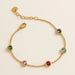 Gold bracelet with colorful gemstones on a beige background
