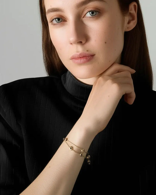 Woman wearing a gold bracelet on her wrist against a neutral background