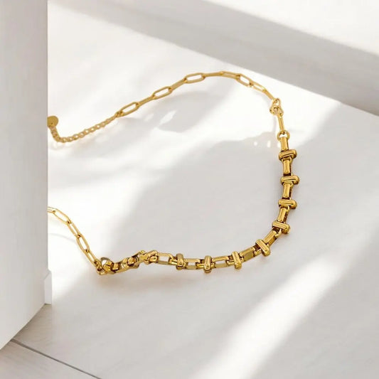 Gold necklace on a white surface with soft shadows