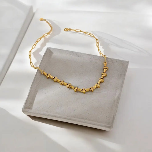 Gold necklace on a gray stone surface with a white background
