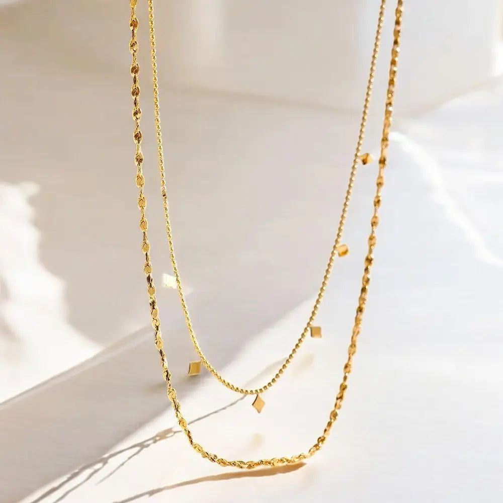 Two gold necklaces on a light background