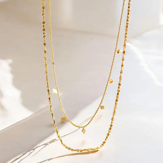 Two gold necklaces on a light background