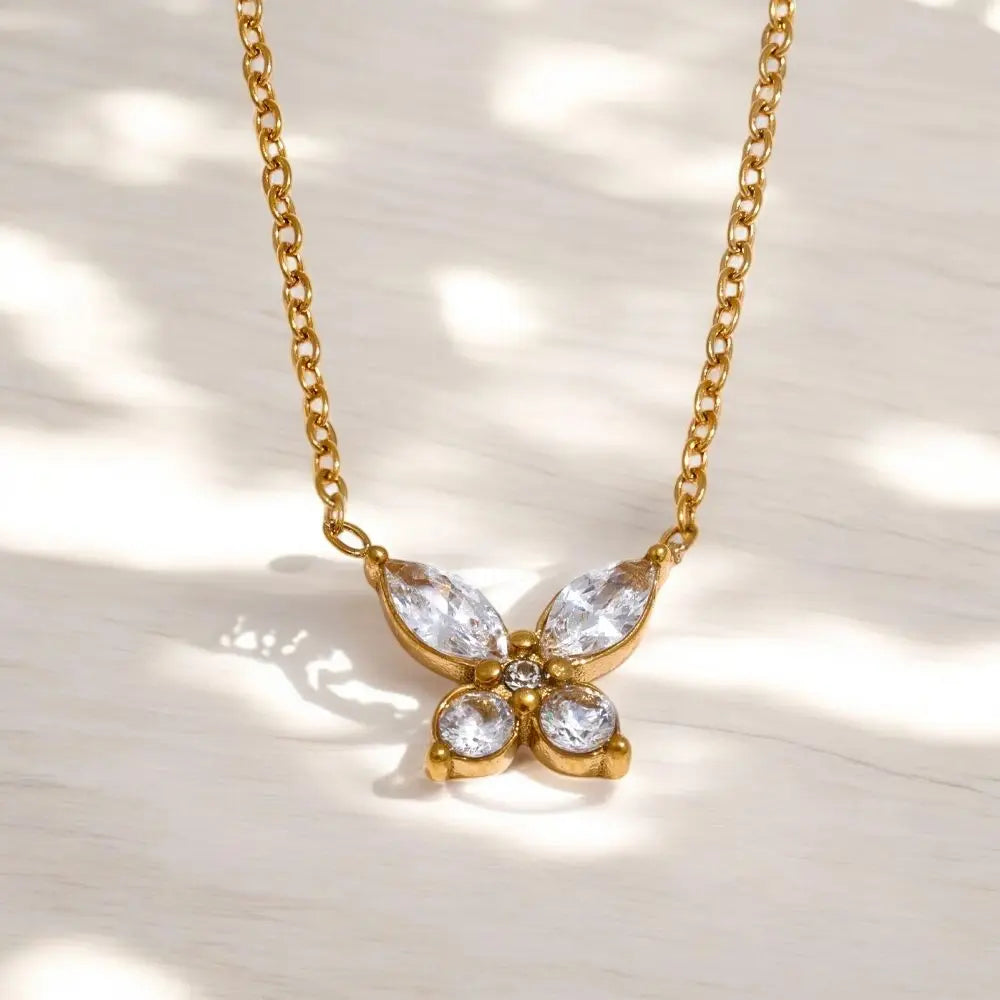 Gold butterfly necklace with clear stones on a light background