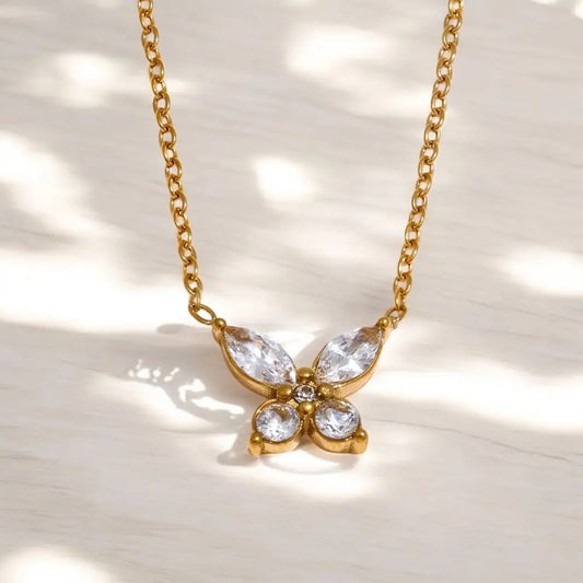 Gold butterfly necklace with clear stones on a light background