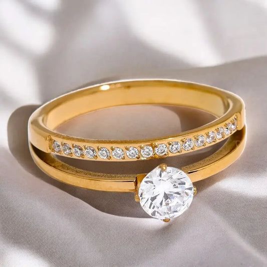 Gold ring with a large diamond and smaller diamonds on a light fabric background