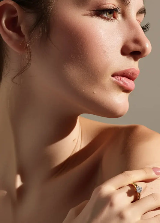 Close-up of a woman wearing a ring with a diamond on a neutral background