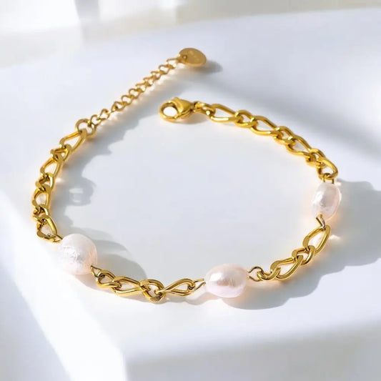 Gold chain bracelet with pink pearls on a white background
