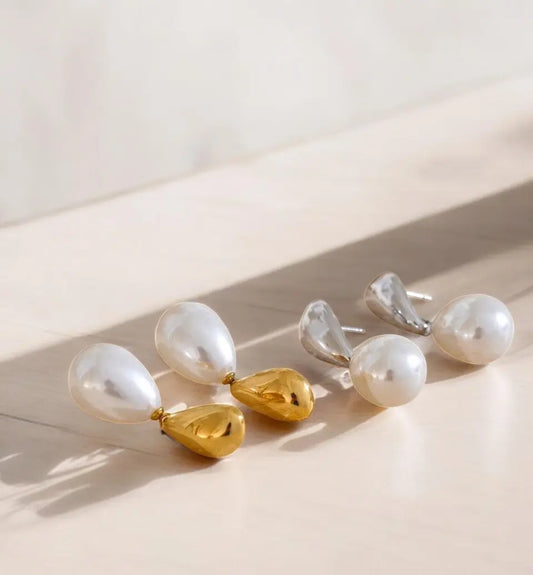 Pearl and gold teardrop earrings on a light surface with soft shadows