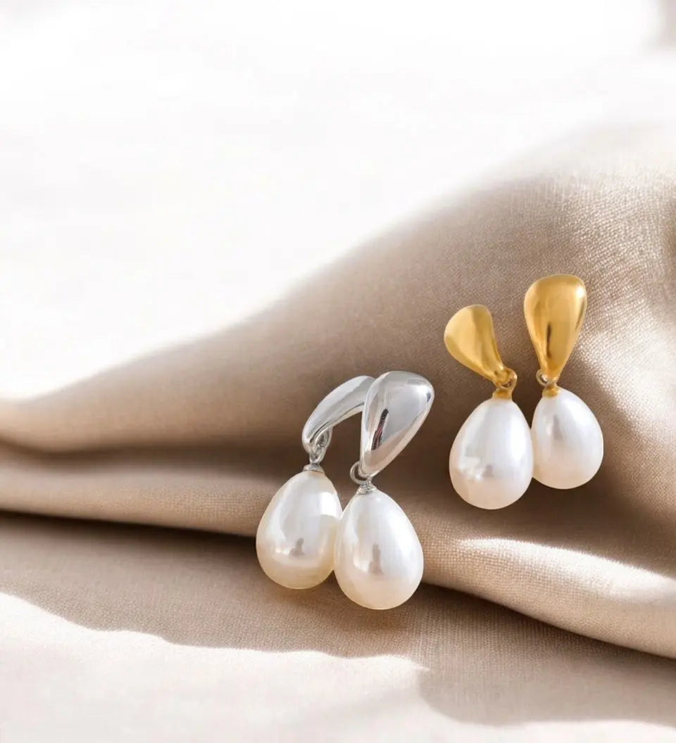 Pair of pearl earrings with gold and silver clasps on a beige fabric background