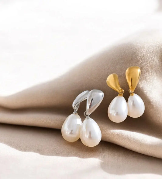 Pair of pearl earrings with gold and silver clasps on a beige fabric background