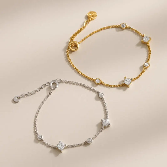 Two gold and silver bracelets with star-shaped stones on a beige background