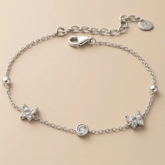 Silver bracelet with butterfly charms on a beige background