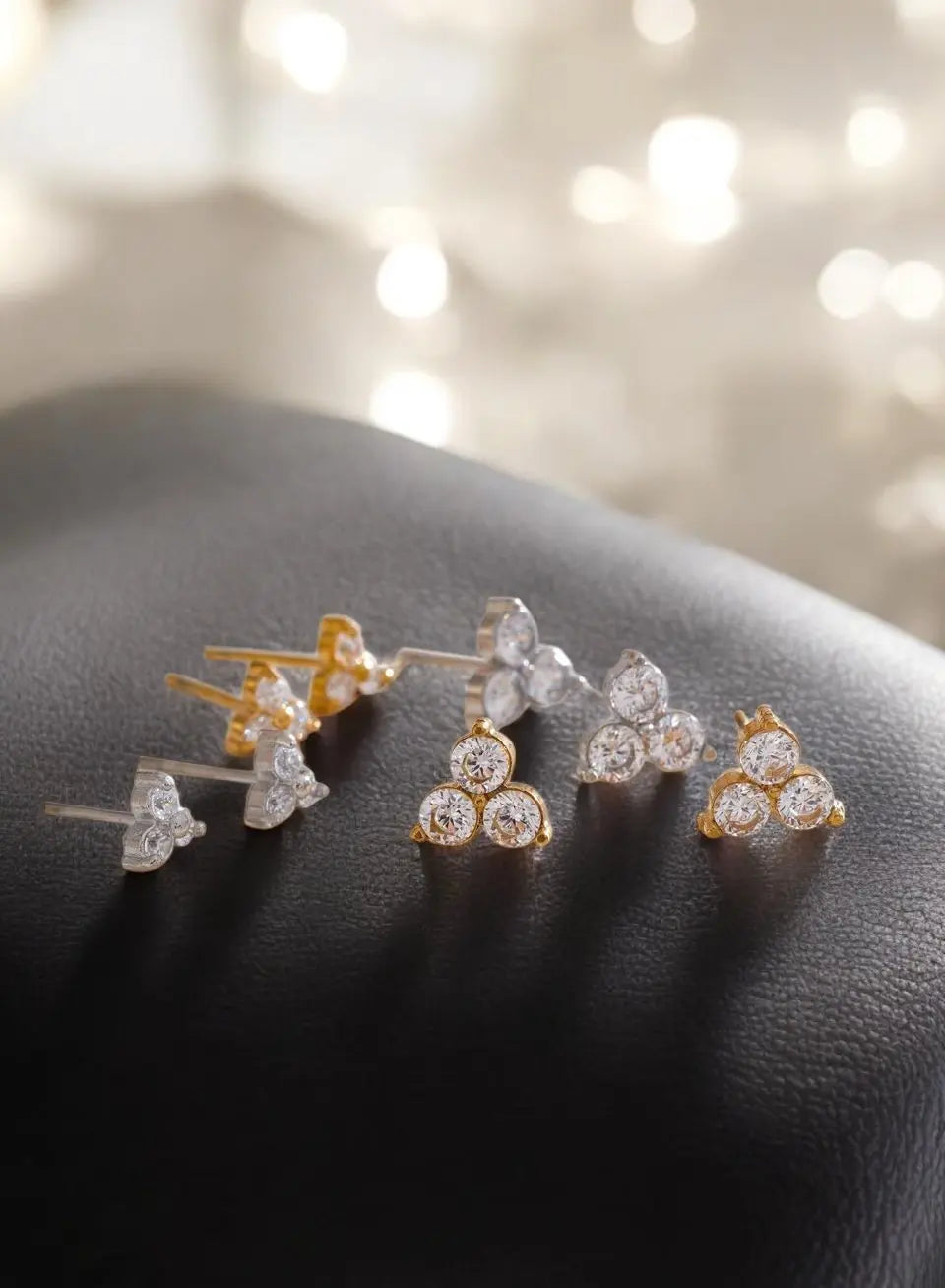 Set of diamond stud earrings on a dark surface with a blurred light background
