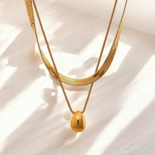 Two gold necklaces on a light background