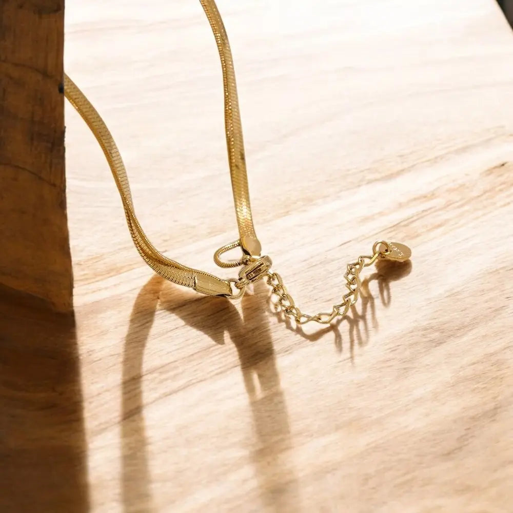 Gold necklace with a lock pendant on a wooden surface